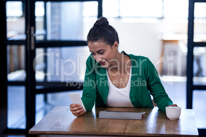 An attractive businesswoman texting and drinking coffee