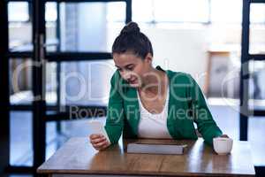 An attractive businesswoman texting and drinking coffee