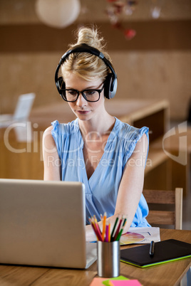 Portait of woman listening music while working at computer