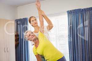 A fitness instructor helping senior doing exercises