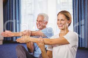 Portrait of fitness instructor and senior stretching their arms