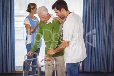 Nurse helping seniors walking with a walker