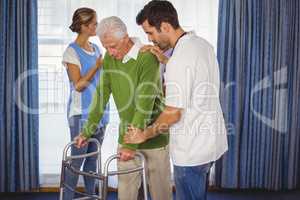 Nurse helping seniors walking with a walker