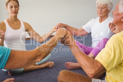 Concentrated seniors holding hands together in circle