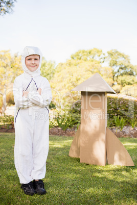 Cute boy with astronaut dress posing next to his cardboard rocke