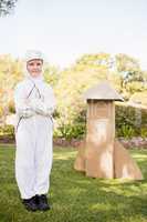 Cute boy with astronaut dress posing next to his cardboard rocke