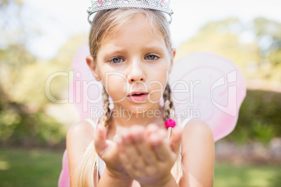 Portrait of cute girl pretending to be a fairy blowing kiss