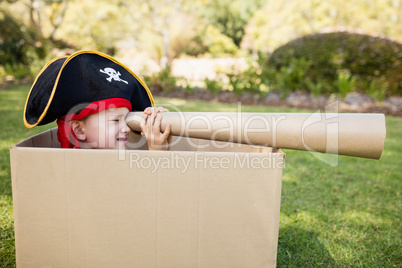 Cute boy pretending to be a pirate playing with cardboard spygla