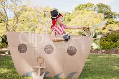 Young boy with fancy dress playing on a cardboard boat