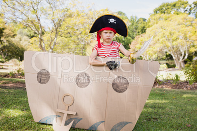 Cute boy with fancy dress posing inside a cardboard boat