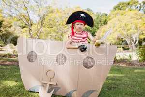 Cute boy with fancy dress posing inside a cardboard boat