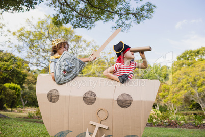 Children with fancy dress playing with a cardboard boat
