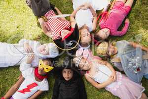 Children with fancy dress lying on the grass and looking the cam