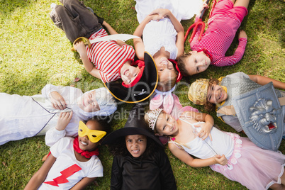 Children with fancy dress lying on the grass and looking the cam