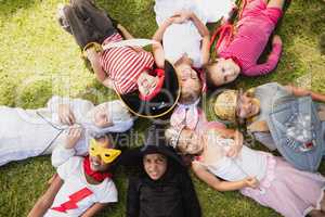 Children with fancy dress lying on the grass and looking the cam