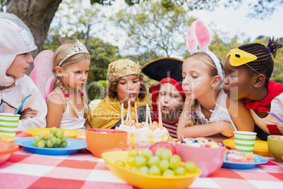 Cute children with fancy dress blowing on the candles together