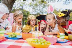 Cute children with fancy dress blowing on the candles together