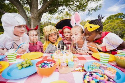 Cute children with fancy dress blowing on the candles together