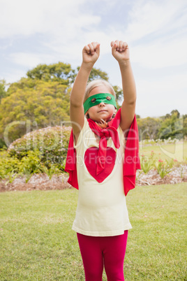 Portrait of young girl with superhero dress raising her arms