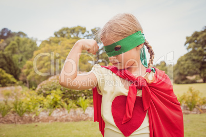 Portrait of young girl with superhero dress showing her muscles