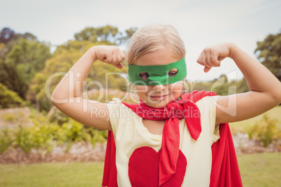 Portrait of young girl with superhero dress showing her muscles