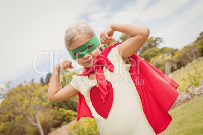 Portrait of young girl with superhero dress showing her muscles