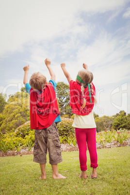 Children with superhero dress front the back raising their arms