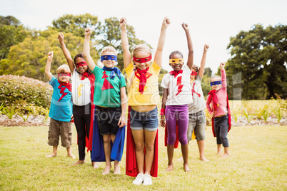 Group of children with superhero dress posing with raised arms