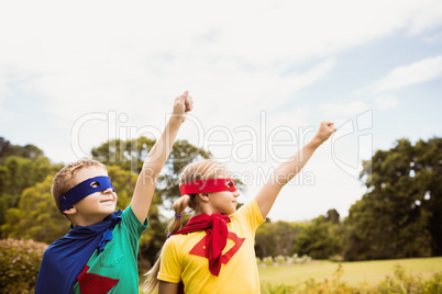 Portrait of children with superhero dress posing with raised arm