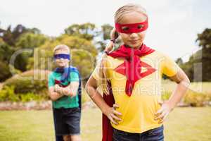 Young girl with superhero dress posing in front of a young boy d
