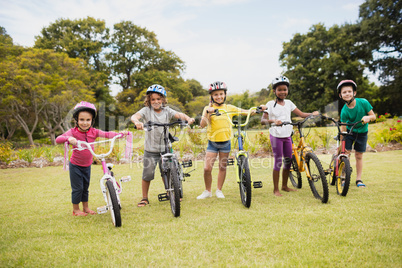 Happy children wearing helmet and posing next to their bike