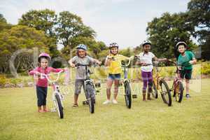Happy children wearing helmet and posing next to their bike