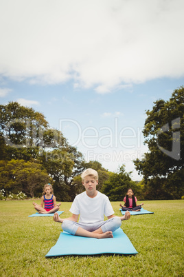 Portrait of a young boy doing yoga with other children