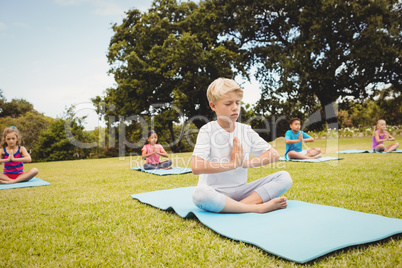 Portrait of a young boy doing yoga with other children