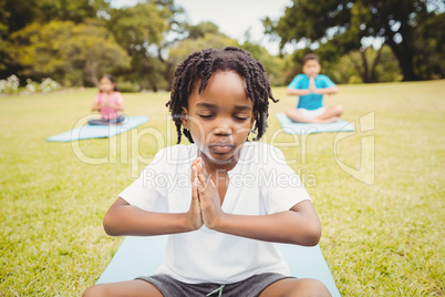 Close up on a young boy doing yoga with other children