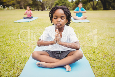 Close up on a young boy doing yoga with other children