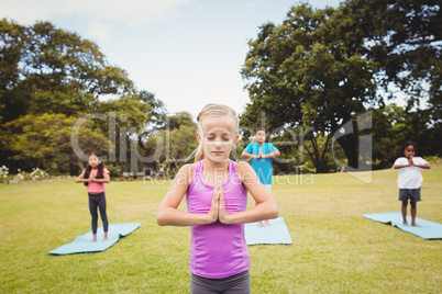 Close up on a young girl doing yoga with other children