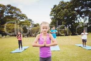 Close up on a young girl doing yoga with other children