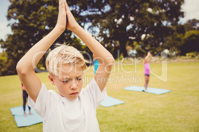 Close up on a young boy doing yoga with other children