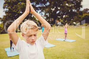 Close up on a young boy doing yoga with other children