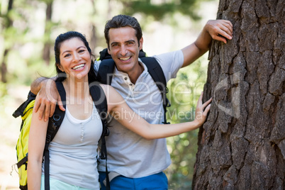 Couple smiling and resting against a tree