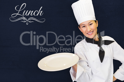 Composite image of smiling female cook holding empty plate in kitchen