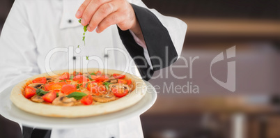 Composite image of close up on a chef holding a pizza