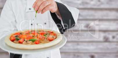 Composite image of close up on a chef holding a pizza