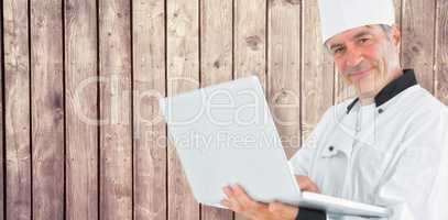 Composite image of friendly chef holding a laptop