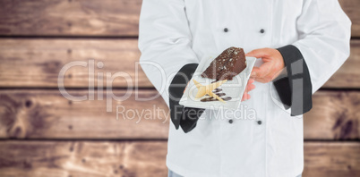 Composite image of close up on a chef holding a chocolate cake