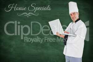 Composite image of chef standing holding a laptop