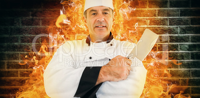 Composite image of portrait of a serious chef holding a knife