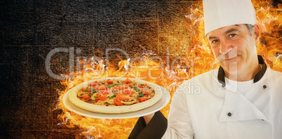 Composite image of friendly chef holding a pizza
