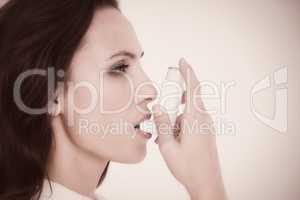 Composite image of asthmatic brunette using her inhaler